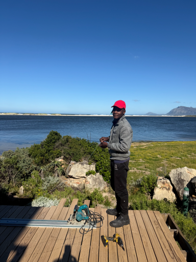 Construction worker at MBIZI lagoon house with Bot River Lagoon and mountains in the background