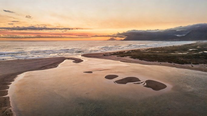 Lagoon / ocean at sunset Bot River Lagoon at sunset with mountain silhouettes and the Atlantic Ocean on the horizon, Hermanus