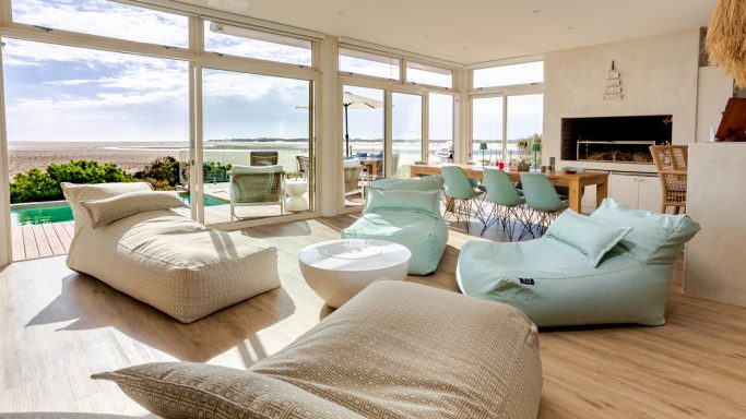 Spacious open-plan living area at MBIZI lagoon house with indoor-outdoor connection to terrace