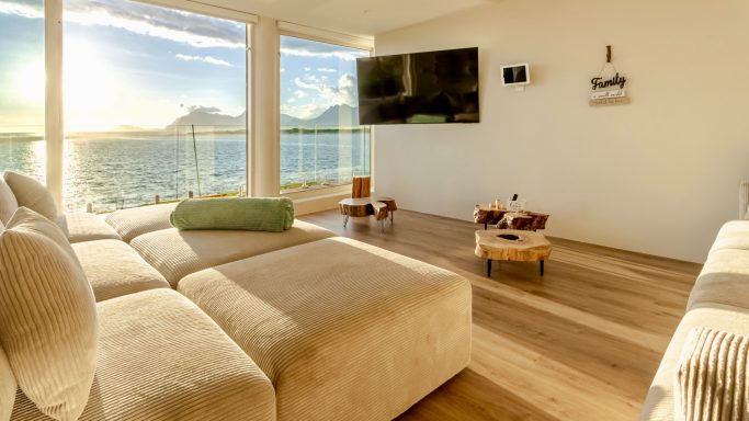 Bright open-plan living room at MBIZI lagoon house with floor-to-ceiling windows and lagoon views