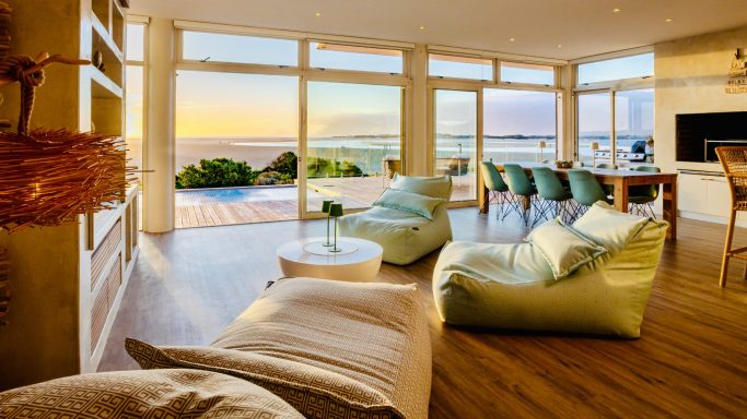 Interior living space at MBIZI lagoon house with warm natural tones and lagoon outlook, Hermanus