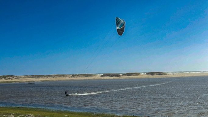 Kitesurfer on Kleinrivier Lagoon near Hermanus with sand dunes and blue South African sky